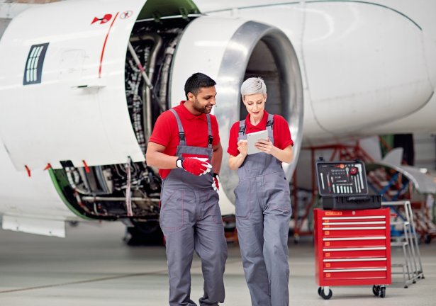 A man and a woman wearing overalls in front of a plane propeller