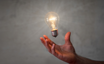 Hand holding lightbulb on grey background Hand holding lightbulb on grey background