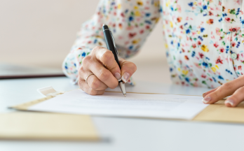 Hand holding pen signing document Hand holding pen signing document