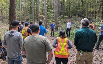 Group of people listening to a speaker during a forest tour.