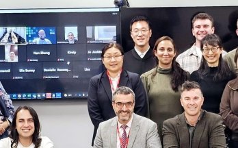 Group photo of peer evaluation participants in New Zealand, with virtual attendees visible on screen.