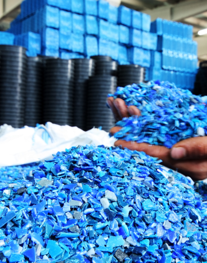 Someone digging their hands into a pile of recycled plastics that are the colour blue