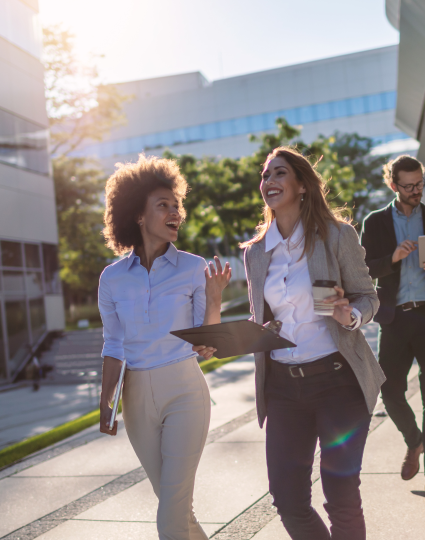 Young group of professionals talking while walking and smiling.