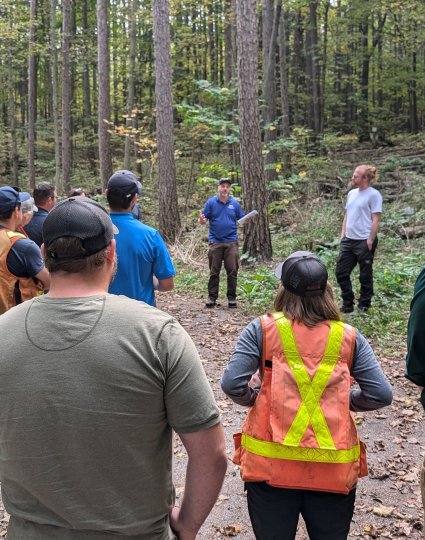 Group of people listening to a speaker during a forest tour.
