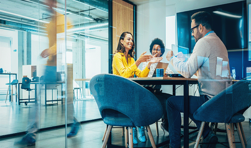 Team of professionals in meeting room smiling while talking.