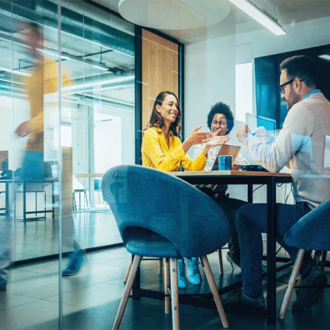 Team of professionals in meeting room smiling while talking.