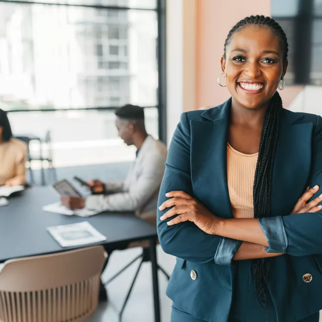 Portrait of a female boss standing arms crossed at work during a meeting.