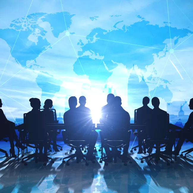 silhouette of group discussion at table with world project in background