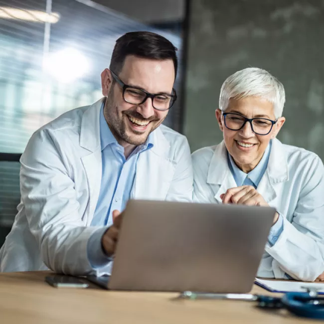 Two colleagues looking at computer smiling