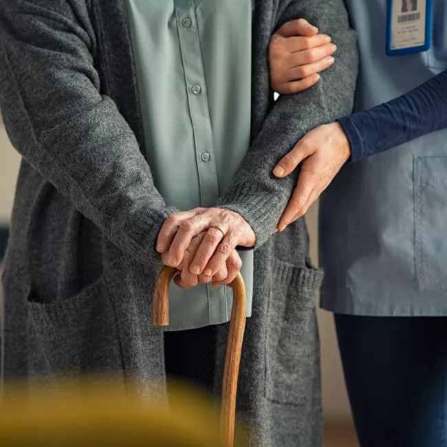 health care worker helping elderly person walk