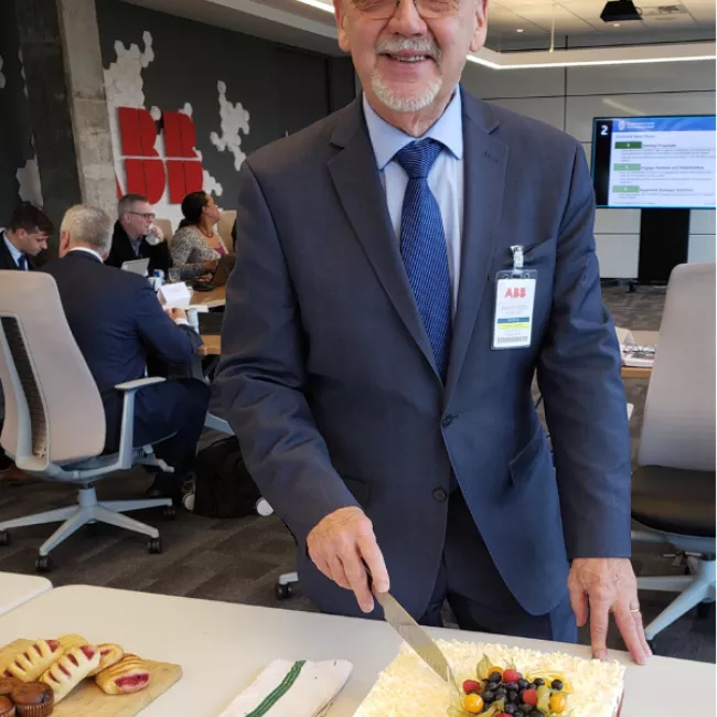 Jacques Régis cutting his cake at a retirement celebration.