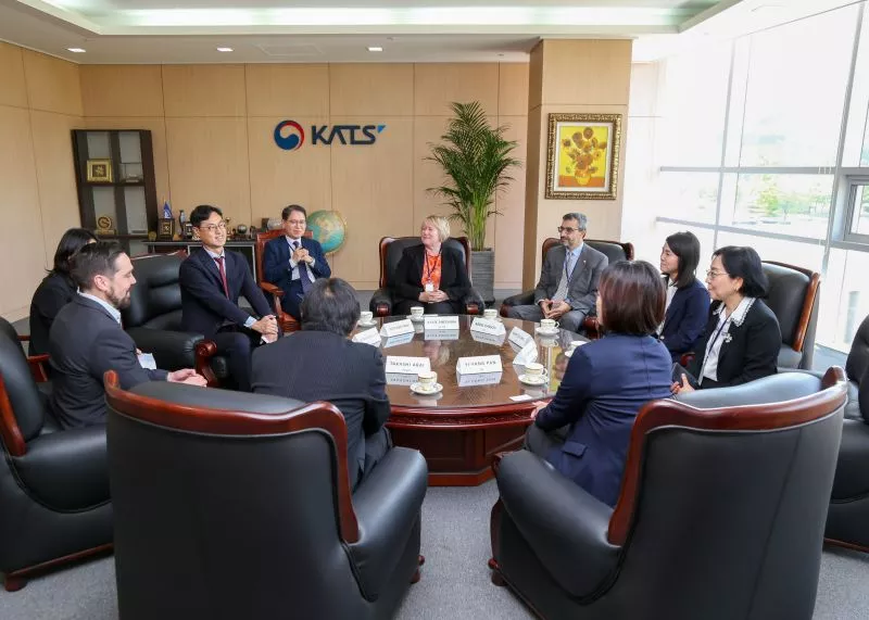 Abdel Kassou and colleagues in a formal meeting at KATS discussing peer evaluations, with the KATS logo in the background.