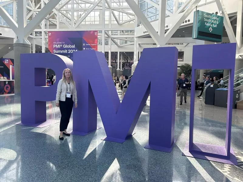 Magdalena Turlejski next to large purple 'PMI' letters at the PMI Global Summit 2024.