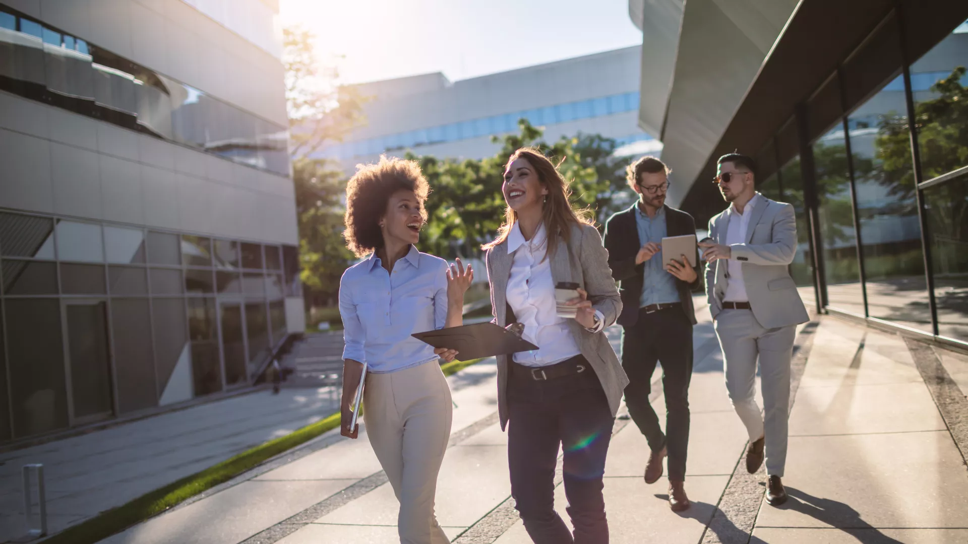 Young group of professionals talking while walking and smiling.